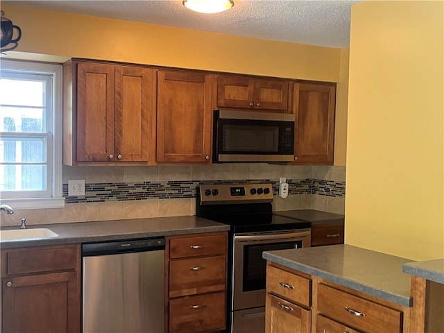 8425 N Tracy Ave, Kansas City, MO 64155 - kitchen with stainless steel appliances, a sink, dark countertops, tasteful backsplash, and brown cabinets