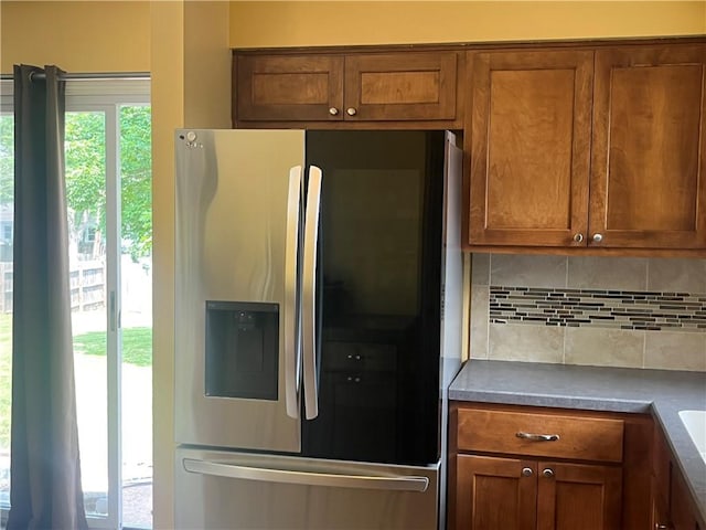 8425 N Tracy Ave, Kansas City, MO 64155 - kitchen with stainless steel fridge with ice dispenser, decorative backsplash, and brown cabinetry
