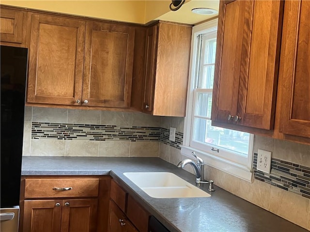 8425 N Tracy Ave, Kansas City, MO 64155 - kitchen with a sink, plenty of natural light, decorative backsplash, and brown cabinetry