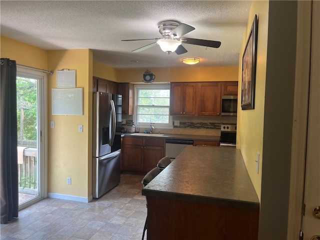 8425 N Tracy Ave, Kansas City, MO 64155 - kitchen with stainless steel appliances, a sink, a ceiling fan, a textured ceiling, and baseboards