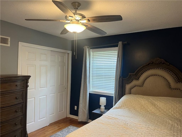 8425 N Tracy Ave, Kansas City, MO 64155 - bedroom with wood finished floors, a textured ceiling, ceiling fan, a closet, and baseboards