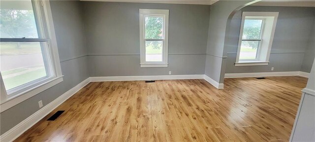 403 S St, Iola, KS 66749 - empty room featuring arched walkways, healthy amount of natural light, baseboards, light wood-style floors, and ornamental molding