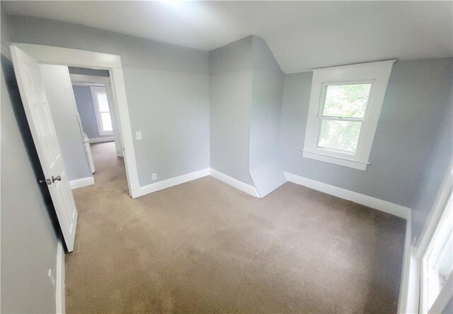 403 S St, Iola, KS 66749 - empty room featuring carpet, plenty of natural light, baseboards, and lofted ceiling