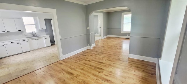 403 S St, Iola, KS 66749 - corridor featuring arched walkways, ornamental molding, a sink, baseboards, and light wood-style floors