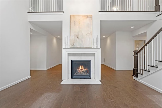 1810 S 98th St, Edwardsville, KS 66111 - unfurnished living room with wood finished floors, stairway, a fireplace, a high ceiling, and recessed lighting