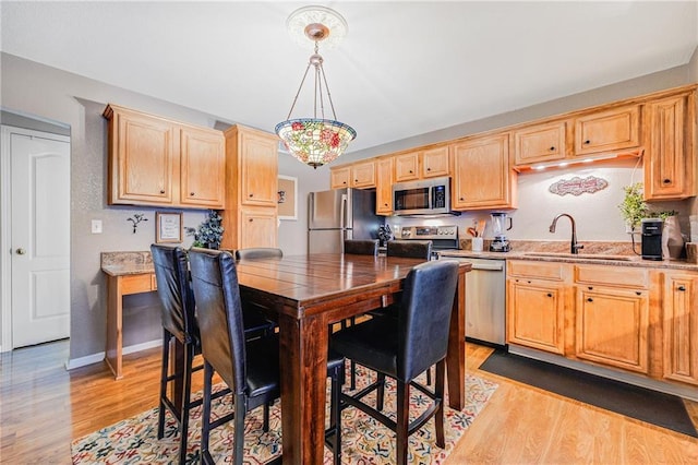 3222 SW Shadow Brook Dr, Blue Springs, MO 64015 - kitchen featuring stainless steel appliances, light wood-style floors, light brown cabinets, hanging light fixtures, and light stone countertops