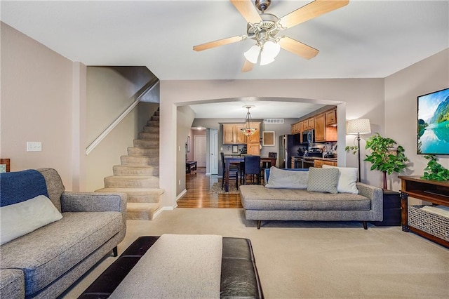 3222 SW Shadow Brook Dr, Blue Springs, MO 64015 - living room with arched walkways, light carpet, stairs, and a ceiling fan