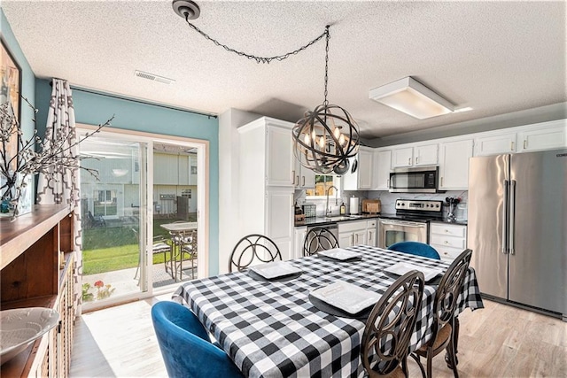 1404 SE Lexington Ave, Lees Summit, MO 64081 - dining room featuring a chandelier, a textured ceiling, and light wood-style floors