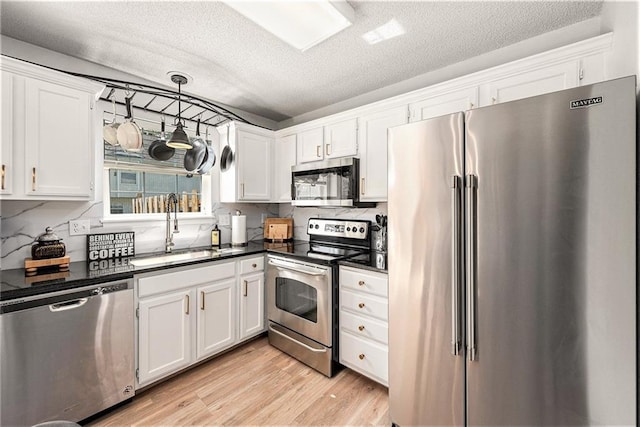 1404 SE Lexington Ave, Lees Summit, MO 64081 - kitchen with stainless steel appliances, a sink, dark countertops, white cabinets, and a textured ceiling