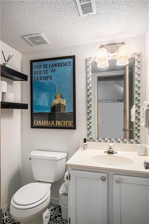1404 SE Lexington Ave, Lees Summit, MO 64081 - bathroom featuring toilet, vanity, and a textured ceiling