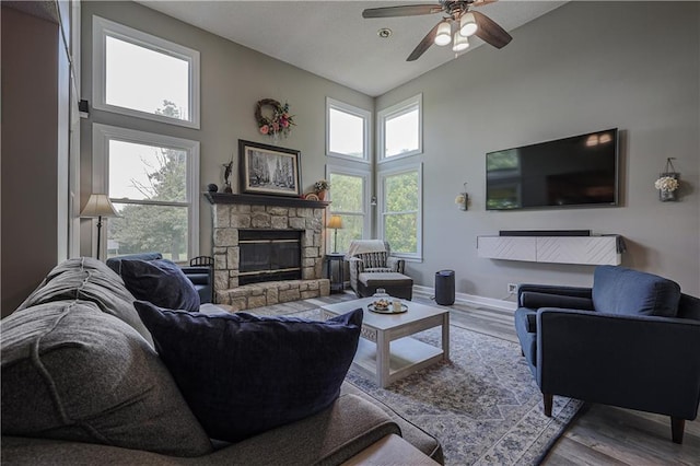 11702 E 246th St, Peculiar, MO 64078 - living area featuring a stone fireplace, ceiling fan, wood finished floors, and high vaulted ceiling