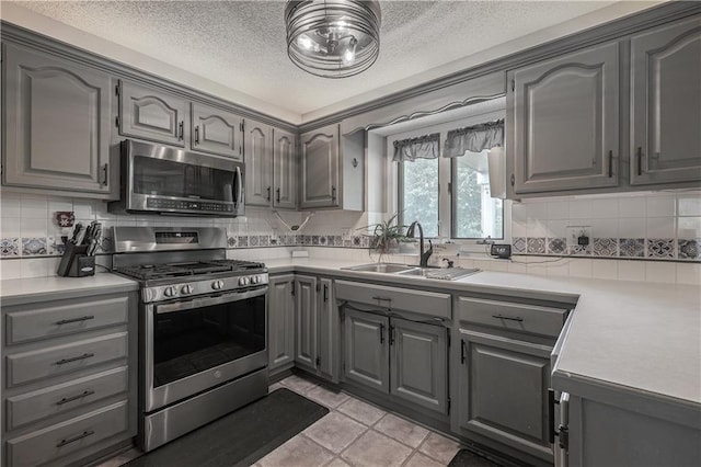 11702 E 246th St, Peculiar, MO 64078 - kitchen featuring appliances with stainless steel finishes, gray cabinets, a textured ceiling, backsplash, and light countertops