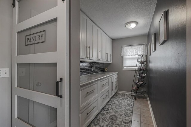 11702 E 246th St, Peculiar, MO 64078 - laundry area with light tile patterned flooring and a textured ceiling