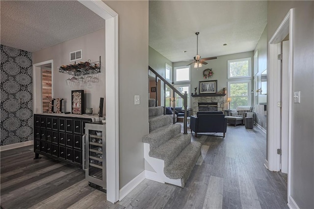 11702 E 246th St, Peculiar, MO 64078 - living room featuring wine cooler, wood finished floors, a ceiling fan, a textured ceiling, and a stone fireplace