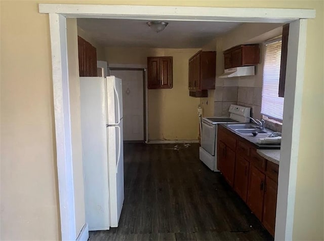 8201 Lydia Ave, Kansas City, MO 64131 - kitchen with white appliances, under cabinet range hood, dark wood-style floors, a sink, and brown cabinetry