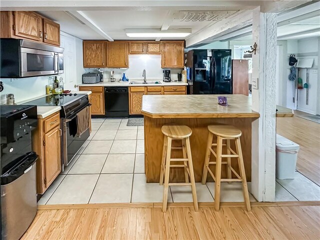 15157 Bass Cove Rd, Gravois Mills, MO 65037 - kitchen with black appliances, a sink, light countertops, brown cabinets, and a breakfast bar