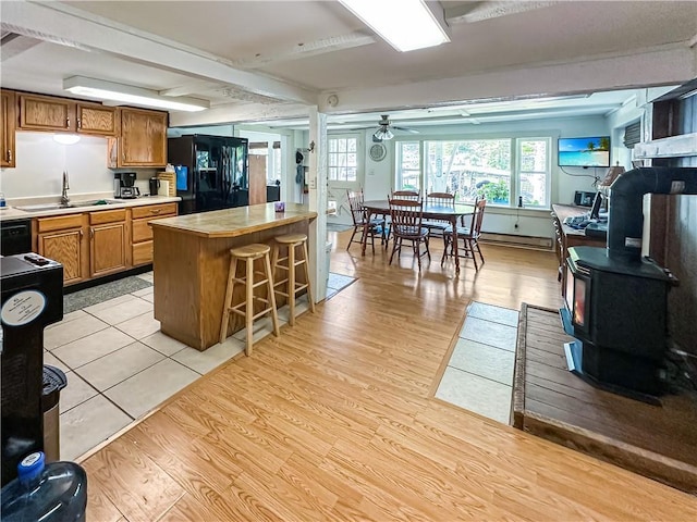 15157 Bass Cove Rd, Gravois Mills, MO 65037 - kitchen with black fridge, a sink, a wood stove, light countertops, and a breakfast bar