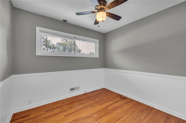 7316 E 109th St, Kansas City, MO 64134 - empty room featuring wood finished floors, ceiling fan, baseboards, and a wainscoted wall