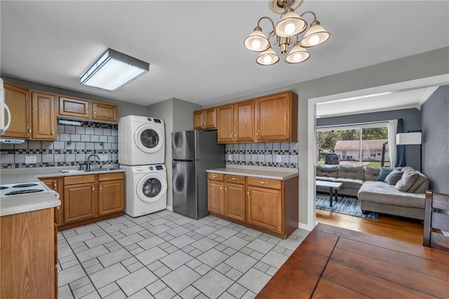 7316 E 109th St, Kansas City, MO 64134 - laundry area with stacked washing machine and dryer and a chandelier