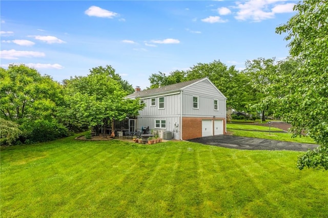 8726 W 104th St, Overland Park, KS 66212 - rear view of house with an attached garage, driveway, central AC, brick siding, and a yard