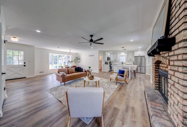 10409 Russell St, Overland Park, KS 66212 - living area with a ceiling fan, light wood-type flooring, recessed lighting, a brick fireplace, and baseboards