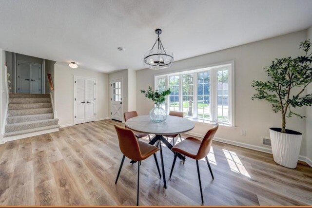 10409 Russell St, Overland Park, KS 66212 - dining space featuring stairway, a chandelier, baseboards, and light wood-style floors