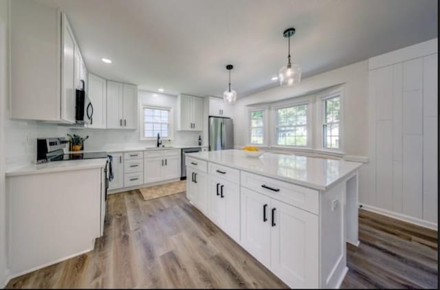 10409 Russell St, Overland Park, KS 66212 - kitchen featuring stainless steel appliances, a sink, light wood-style flooring, light countertops, and white cabinetry