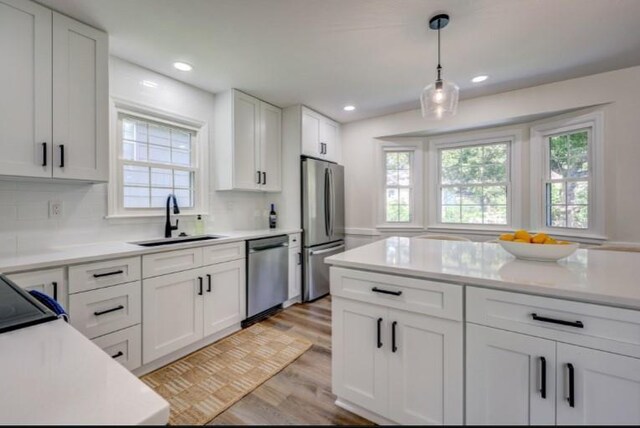 10409 Russell St, Overland Park, KS 66212 - kitchen featuring stainless steel appliances, a sink, light countertops, light wood-type flooring, and white cabinets