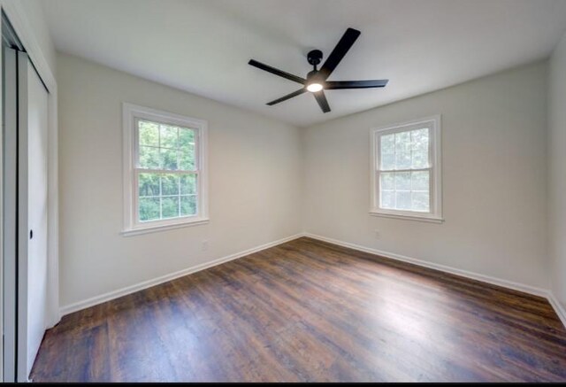 10409 Russell St, Overland Park, KS 66212 - unfurnished bedroom featuring multiple windows, dark wood-style flooring, baseboards, and a closet