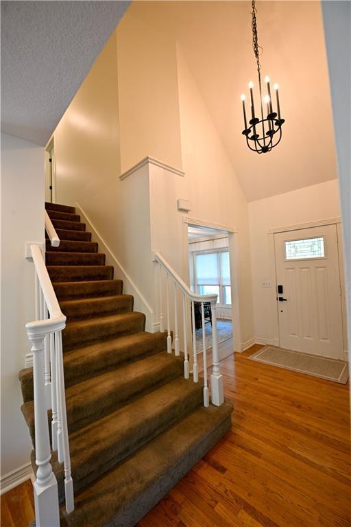 17586 W 112th St, Olathe, KS 66061 - entrance foyer featuring stairway, a chandelier, high vaulted ceiling, wood finished floors, and baseboards