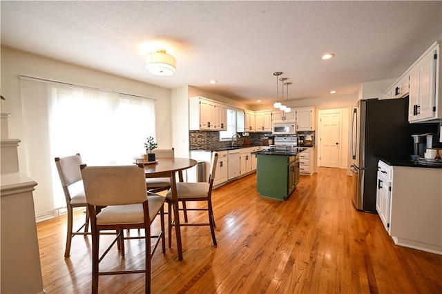 17586 W 112th St, Olathe, KS 66061 - kitchen with white appliances, a kitchen island, a sink, light wood finished floors, and recessed lighting