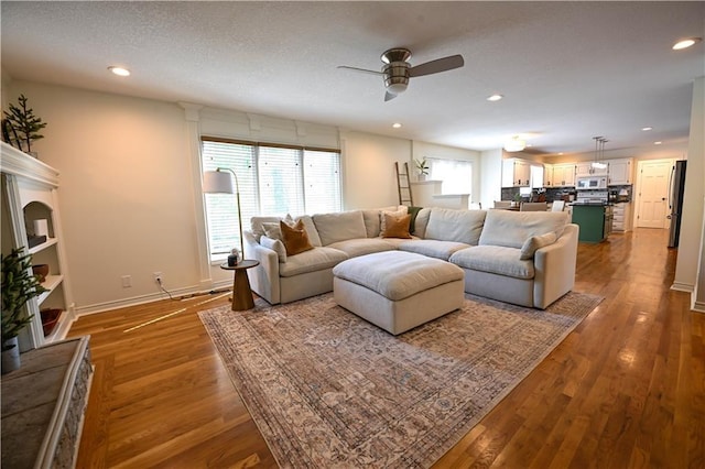 17586 W 112th St, Olathe, KS 66061 - living room featuring a ceiling fan, wood finished floors, recessed lighting, baseboards, and a fireplace with raised hearth