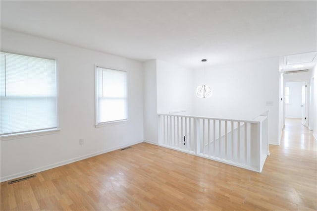 956 Ridge Dr, Warrensburg, MO 64093 - unfurnished room featuring light wood finished floors, baseboards, attic access, and a chandelier