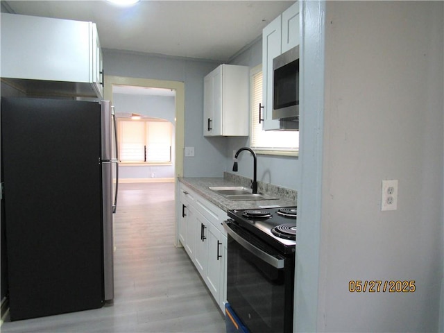 2119 N 32nd St Unit K, Kansas City, KS 66104 - kitchen with appliances with stainless steel finishes, a sink, white cabinets, light wood-style flooring, and light countertops