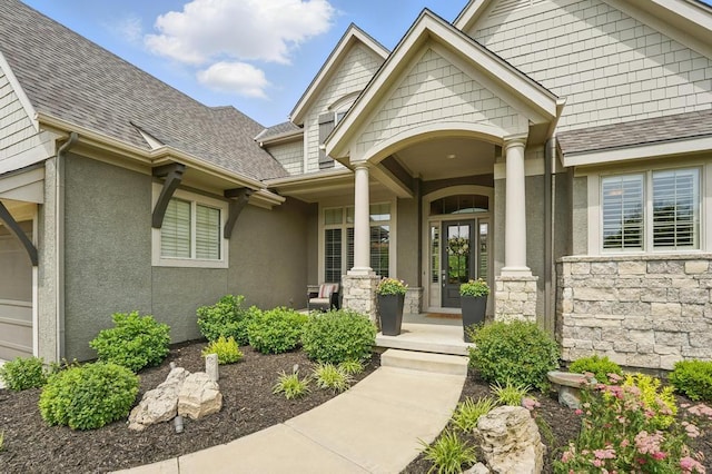 16005 Melrose St, Overland Park, KS 66221 - view of exterior entry featuring a porch, roof with shingles, stone siding, and stucco siding