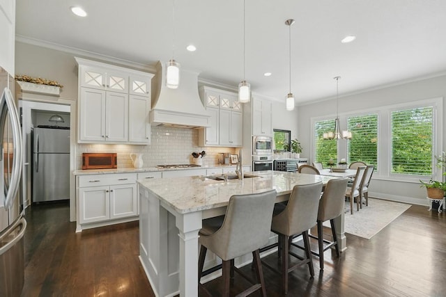 16005 Melrose St, Overland Park, KS 66221 - kitchen featuring appliances with stainless steel finishes, wall chimney range hood, dark wood finished floors, a kitchen island with sink, and crown molding