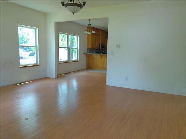 503 W Shawnee St, Paola, KS 66071 - unfurnished living room with light wood-type flooring and a chandelier