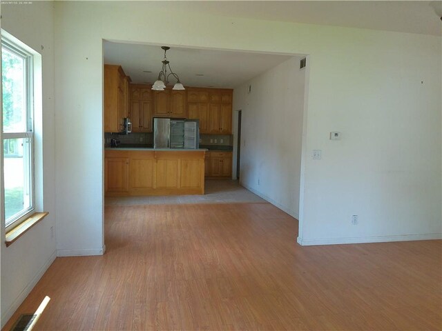 503 W Shawnee St, Paola, KS 66071 - kitchen with light wood-style floors, backsplash, baseboards, hanging light fixtures, and a peninsula