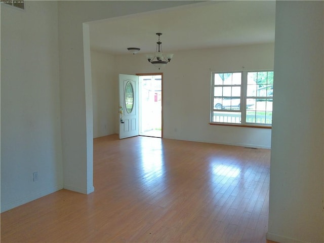 503 W Shawnee St, Paola, KS 66071 - empty room featuring light wood-type flooring, baseboards, and a chandelier