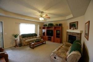 814 Clancy Ct, Raymore, MO 64083 - living room with a ceiling fan, a tray ceiling, a fireplace, and carpet floors