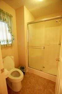 814 Clancy Ct, Raymore, MO 64083 - bathroom featuring a shower stall, toilet, and tile patterned floors