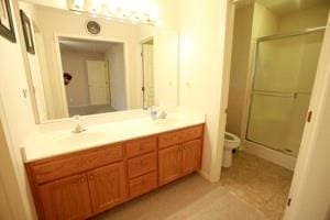 814 Clancy Ct, Raymore, MO 64083 - bathroom featuring toilet, a stall shower, double vanity, and tile patterned floors
