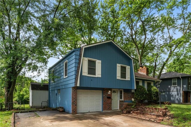 6401 E 120th Ter, Grandview, MO 64030 - split level home with a gambrel roof, a garage, concrete driveway, and brick siding