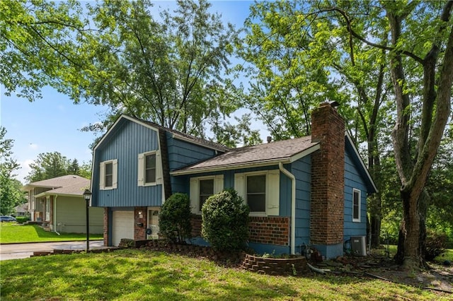 6401 E 120th Ter, Grandview, MO 64030 - tri-level home with a chimney, an attached garage, brick siding, concrete driveway, and a front lawn