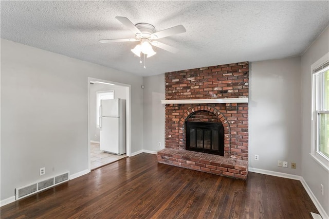 6401 E 120th Ter, Grandview, MO 64030 - unfurnished living room featuring wood finished floors, a ceiling fan, a textured ceiling, healthy amount of natural light, and baseboards