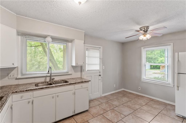 6401 E 120th Ter, Grandview, MO 64030 - kitchen featuring freestanding refrigerator, a sink, plenty of natural light, white cabinetry, and a textured ceiling