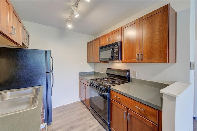 600 E 8th St Unit 5N, Kansas City, MO 64106 - kitchen featuring black appliances, light wood finished floors, brown cabinets, baseboards, and a sink