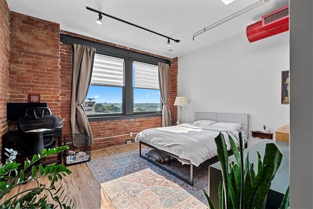 700 Broadway Blvd Unit 507, Kansas City, MO 64105 - bedroom with track lighting, a wood stove, wood finished floors, and brick wall