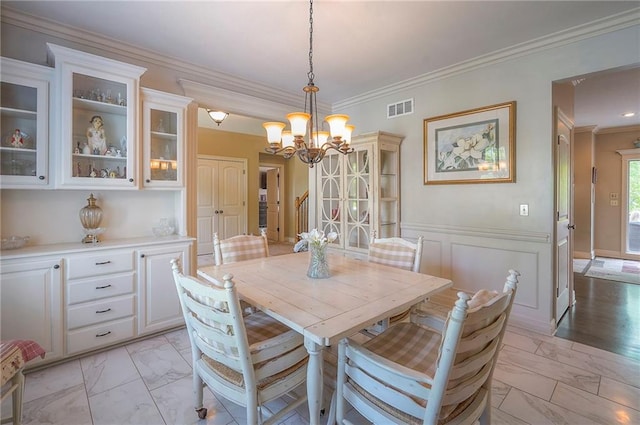 309 E 126th St, Kansas City, MO 64145 - dining area featuring light marble finish floors, a chandelier, crown molding, and wainscoting