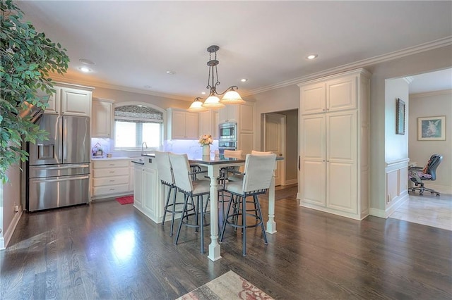309 E 126th St, Kansas City, MO 64145 - kitchen featuring appliances with stainless steel finishes, a breakfast bar, a kitchen island, ornamental molding, and pendant lighting